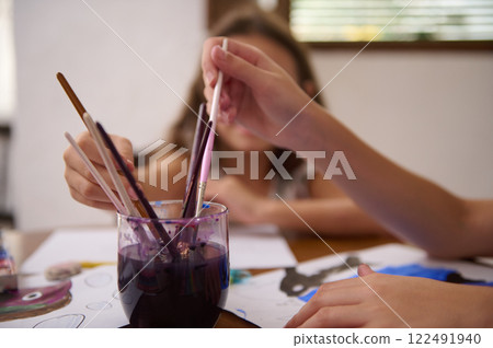 Hands painting with brushes and watercolors during creative art activity 122491940