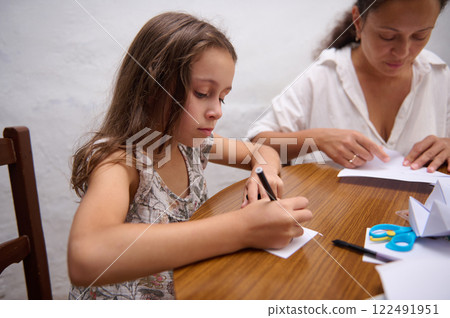 Mother and daughter together crafting arts at a wooden table Mother and daughter together crafting arts at a wooden table 122491951