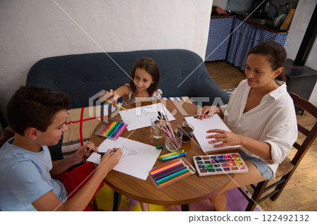 Family Enjoying Art Projects Together at Home Around a Wooden Table Family Enjoying Art Projects Together at Home Around a Wooden Table 122492132
