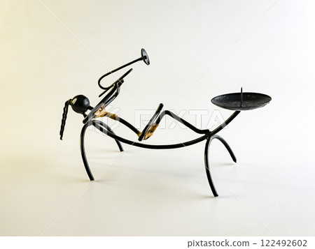 A candlestick made of black wire in the shape of a woman playing a trumpet on a white background A candlestick made of black wire in the shape of a woman playing a trumpet on a white background 122492602