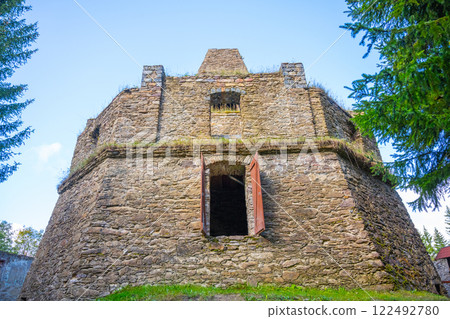 The remnants of a historic lime kiln stand near Kovarska, surrounded by lush greenery. The structure features large openings and aged stones, reflecting its industrial past in the Ore Mountains. The remnants of a historic lime kiln stand near Kovarska, surrounded by lush greenery. The structure features large openings and aged stones, reflecting its industrial past in the Ore Mountains. 122492780