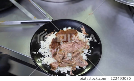 Savory Pulled Lamb and White Rice on a Black Plate 122493080