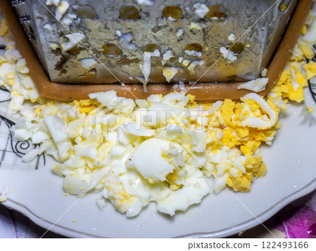 Grated egg. Protein. protein product.  Grated boiled egg on a kitchen board. 122493166