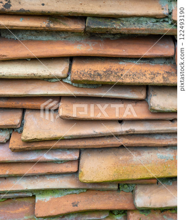 Background from the old tiled masonry. Orange tiles. Wall made of clay fragments. 122493190