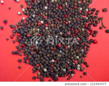 Peppercorns on a red background. Red, white and black peppercorns. Seasoning for dishes. The concept of spicy food. Spicy condiment. Cooking. Peppercorns on a red background. Red, white and black peppercorns. Seasoning for dishes. The concept of spicy food. Spicy condiment. Cooking. 122493477
