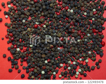 Peppercorns on a red background. Red, white and black peppercorns. Seasoning for dishes. The concept of spicy food. Spicy condiment. Cooking. Peppercorns on a red background. Red, white and black peppercorns. Seasoning for dishes. The concept of spicy food. Spicy condiment. Cooking. 122493478