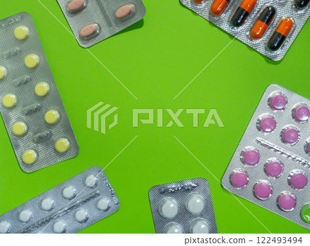 Pills of different colors on a green background.  concept of medical drugs. Place for an inscription. Medical treatment. 122493494