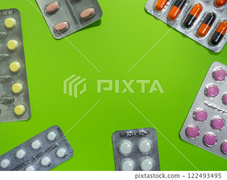 Pills of different colors on a green background.  concept of medical drugs. Place for an inscription. Medical treatment. 122493495