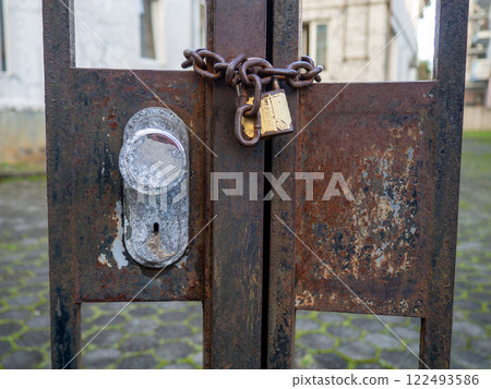 Gate lock. Padlock in action. Rusty chains and gates. No entry. 122493586