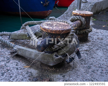rope goes into the water from the bollard. Attaching boats to the pier. Port area. Sea port. 122493591