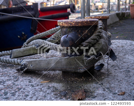 rope goes into the water from the bollard. Attaching boats to the pier. Port area. Sea port. 122493593