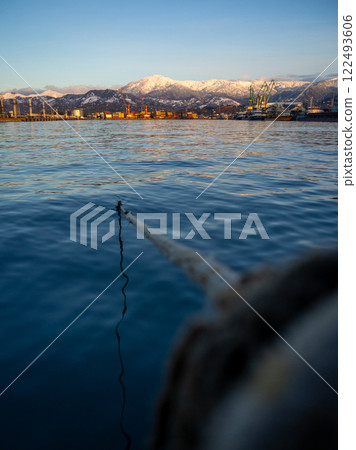 rope goes into the water from the bollard. Attaching boats to the pier. Port area. Sea port. A taut rope. rope goes into the water from the bollard. Attaching boats to the pier. Port area. Sea port. A taut rope. 122493606