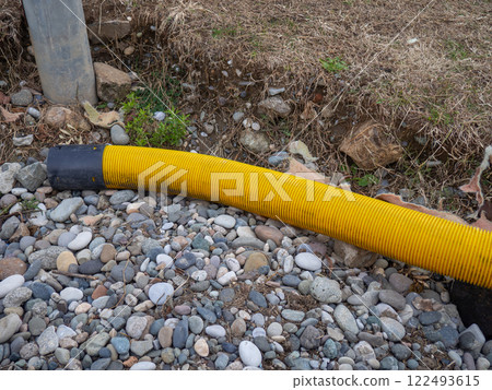 Yellow pipe on stone pebbles. Technical communications on the beach. Cable. 122493615