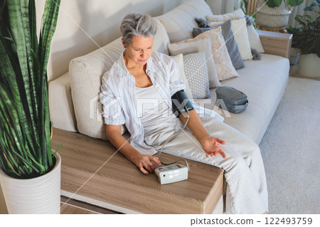 Concept health. An elderly beautiful gray-haired woman measures blood pressure 122493759