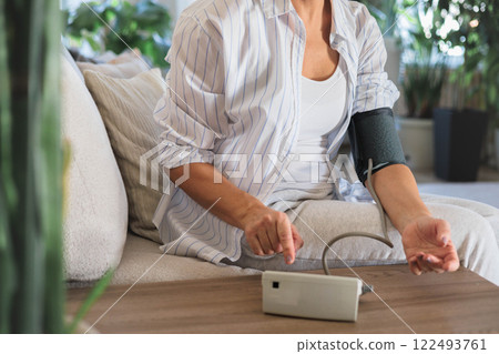 Women's hands with a tonometer close up. A woman measures her own blood pressure while Women's hands with a tonometer close up. A woman measures her own blood pressure while 122493761