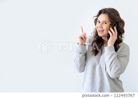 Beautiful European woman in gray knitted suit smiles, looks at camera and calls on phone Beautiful European woman in gray knitted suit smiles, looks at camera and calls on phone 122493767