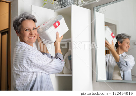 Beautiful elderly woman pensioner with gray hair putting first aid kit with vitamins, drugs 122494019