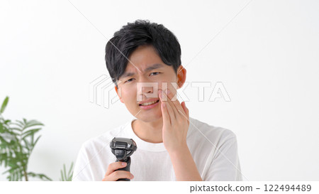 Man shaving with an electric shaver Man shaving with an electric shaver 122494489