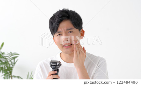 Man shaving with an electric shaver 122494490