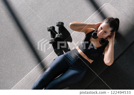 Beautiful athletic Asian woman trains in gymnastics studio, enjoys flexibility, healthy lifestyle  122494533