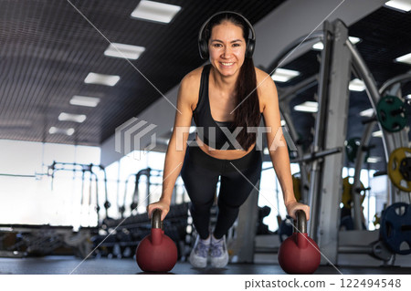 Young beautiful asian woman doing push ups with weights in gym 122494548