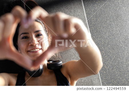 Beautiful athletic Asian woman trains in gymnastics studio, enjoys flexibility, well-being 122494559