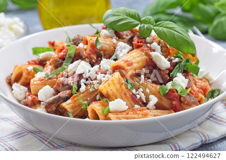 Rigatoni alla Norma pasta with eggplant and tomato, basil and ricotta salata, horizontal closeup 122494627