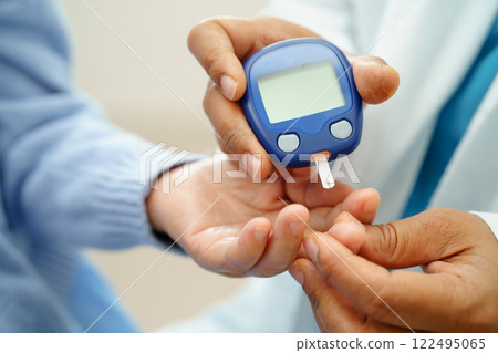 Asian doctor using digital glucose meter for check sample blood sugar level to treatment diabetes. 122495065