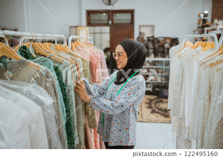 A young woman is shopping for fashionable clothing items in a chic boutique 122495160