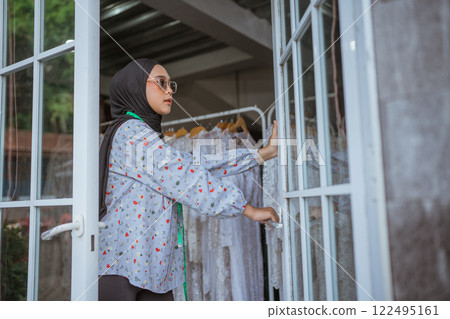 A Trendy, Young Woman Steps Into a Boutique Showcasing Fashionable Clothing Options 122495161