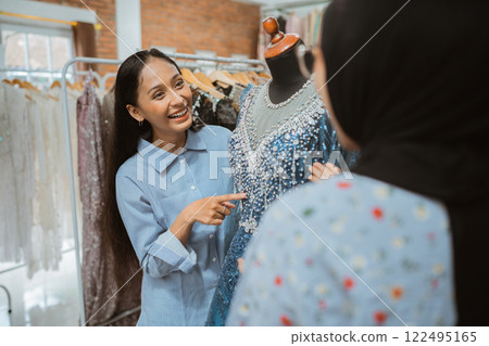 An Excited Designer is Showcasing a Beautifully Elegant Dress in a Fashion Studio An Excited Designer is Showcasing a Beautifully Elegant Dress in a Fashion Studio 122495165