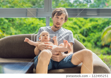 An exhausted father falls asleep on the couch while holding his 3-month-old baby in his arms. A tender and heartwarming moment showcasing love, caregiving, and the challenges of parenthood. Family and An exhausted father falls asleep on the couch while holding his 3-month-old baby in his arms. A tender and heartwarming moment showcasing love, caregiving, and the challenges of parenthood. Family and 122495251