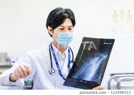Young doctor looking at an X-ray and diagnosing Young doctor looking at an X-ray and diagnosing 122496553