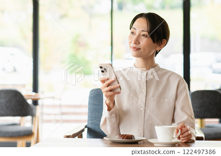 A middle-aged woman relaxing at a cafe A middle-aged woman relaxing at a cafe 122497386