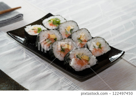 Homemade salmon salad sushi on black plate with white placemat on table. Japanese healthy food. Selective focus. Homemade salmon salad sushi on black plate with white placemat on table. Japanese healthy food. Selective focus. 122497450