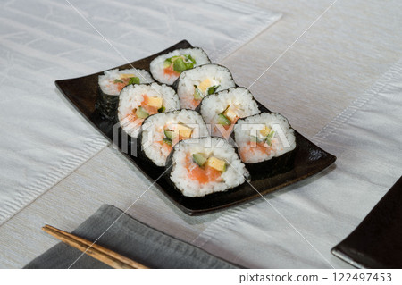Homemade salmon salad sushi on black plate with white placemat on table. Japanese healthy food. Selective focus. 122497453