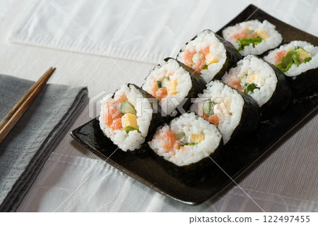 Homemade salmon salad sushi on black plate with white placemat on table. Japanese healthy food. Selective focus. 122497455