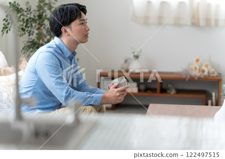 A man in his 30s sitting on a sofa A man in his 30s sitting on a sofa 122497515