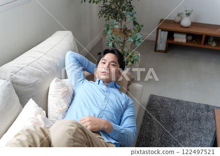 Man lying on sofa in living room 122497521