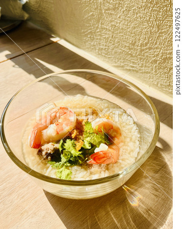 Breakfast seafood prawn boiled rice in glass bowl on the table with shining light in the morning Breakfast seafood prawn boiled rice in glass bowl on the table with shining light in the morning 122497625