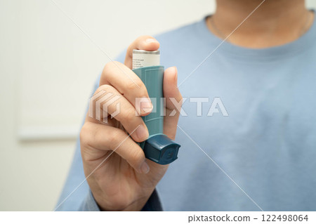 Asthma and chronic obstructive pulmonary disease COPD, Asian young man using metered dose inhaler MDI. 122498064