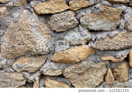 Textured wall crafted from natural stones showcasing rustic charm in muted tones 122501193