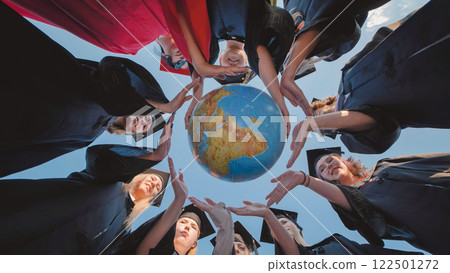 Students in graduation gowns encircling a globe, signaling their preparedness for international opportunities 122501272