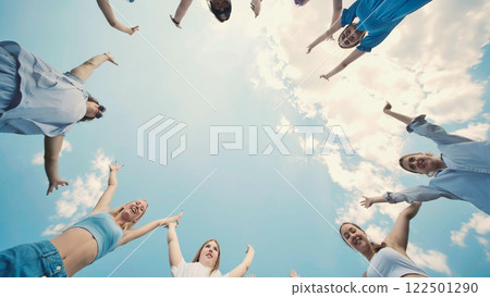 Happy students join hands in a circle, reaching for the sky to celebrate their friendship and academic achievements 122501290
