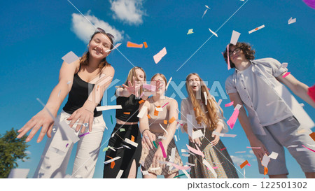 Group of five exuberant high school students joyfully tossing vibrant confetti in the air to celebrate their graduation day 122501302