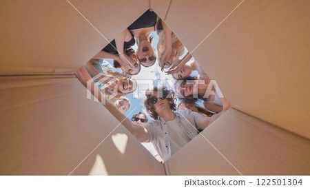 Happy high school students discovering a fun summer surprise inside a large cardboard box 122501304