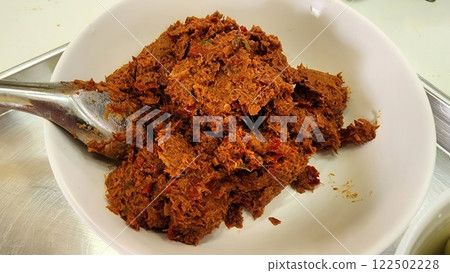 Curry paste for Thai cooking. Spicy chili paste in white bowl on stainless steel surface. Curry paste for Thai cooking. Spicy chili paste in white bowl on stainless steel surface. 122502228