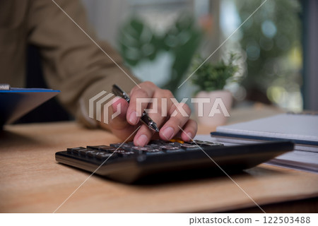 man accountant is pressing a calculator calculating income tax financial, planning and managing investment and saving according to the goal. man accountant is pressing a calculator calculating income tax financial, planning and managing investment and saving according to the goal. 122503488