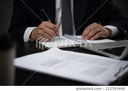 Man holding pen in hand writing journal, agenda or research. Business on desk. Writing planner notebook on paper Man holding pen in hand writing journal, agenda or research. Business on desk. Writing planner notebook on paper 122503498