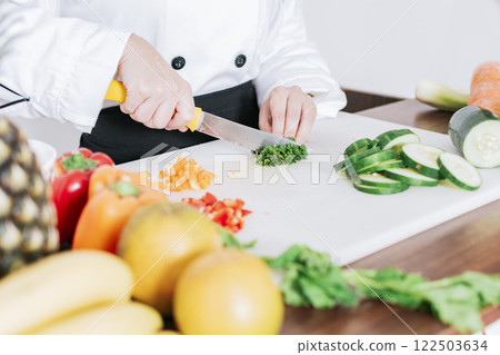 Chef hands preparing and cutting vegetables, Close up of a woman chef cutting vegetables, Hands of female chef cutting vegetables Chef hands preparing and cutting vegetables, Close up of a woman chef cutting vegetables, Hands of female chef cutting vegetables 122503634